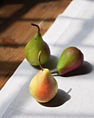 Three pears on a white linen table cloth