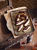 Chocolate and caramel eclairs on an old-fashioned tray