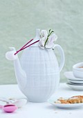 White, retro china coffee pot with fabric butterfly next to plate of biscuits