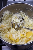 Mashing Potatoes and Swede in a Pot with a Metal Masher