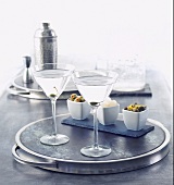 Zwei Martinis auf einem Silbertablett, Oliven, Kapern, Silberzwiebeln und Cocktailshaker