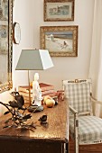 Collection of old ornaments on rustic chest of drawers next to antique country-house chair in corner