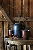 Small deer figurine and vases of twigs on stool in cabin