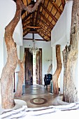 Rustic wooden supports in airy entrance hall with high wood-beamed ceiling