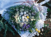 Easter eggs in a wreath of rosemary with violets and daisies