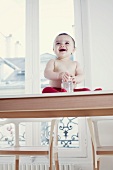 Laughing baby with its bottle sitting on a table