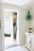 Foyer of summer cottage with pastel blue wooden steps and sun hat and handbag hanging on small coat rack