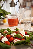 Tomatoes with mozzarella and rocket on a table laid for a meal