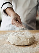Fresh pizza dough being dusted with flour