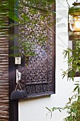 Carved wooden panel on house facade and lantern hanging on tree