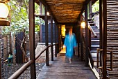 Frau auf überdachtem Holzweg mit Stufen in tropischem Garten