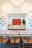 White dining table with wooden inlays and classic, 50s chairs; painting in niche in background