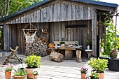 Tree stump stools, table and stacked firewood on terrace of wooden cabin