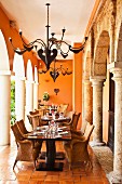 Colonial-style dining area with impressive metal chandeliers between stone columns