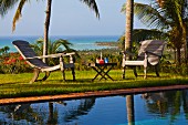 Relaxation area next to pool in garden of palm trees with sea view