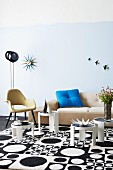 Seating area with small, round retro tables on rug with black and white, 60s-style pattern of circles