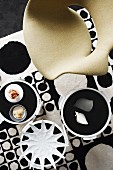 Designer chair and ornaments on side tables on 60s retro-style rug with pattern of black and white circles