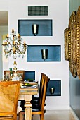 Elegant dining area with crystal candelabra on antique table; silver beakers in blue-painted niches