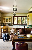 Heavy coffee table and sofa in country-style, open-plan interior with dining area in front of fitted kitchen