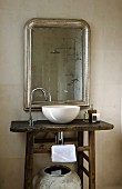 Rustikaler Waschtisch mit weisser Waschschüssel und Designer Armatur vor Spiegel mit Silberrahmen