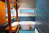 Blaue Mosaikfliesen und Waschtisch mit Einbauten aus Edelholz in einem Badezimmer