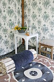 Roll of wooden rods on lounger and side table in corner of tent made of floral fabric