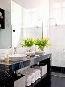 Gelber Tulpenstrauss auf Marmor Waschtisch mit Handtuchfach und Retroarmatur; bodengleiche Dusche im Hintergrund