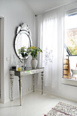 Console with bouquet of flowers, with Venetian wall mirror in corner of room