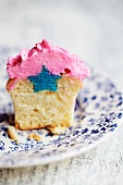 A cupcake with a blue star inside it and pink icing
