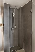 Moderner Duschbereich mit grauen Fliesen und offener Glastür