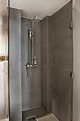 Modern shower area with grey tiles and open glass door