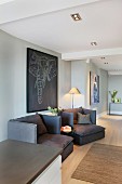Dunkle Sessel vor grauer Wand mit Tiermotiv auf Bild in grossräumigen, modernen Wohnzimmer