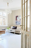 View through open door into living room with modern coffee table and sofa below chandelier