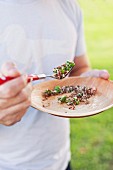 A man eating quinoa salad with barbecue courgette, preserved lemons and asparagus