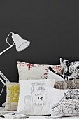 Scatter cushions next to table lamp painted on black wall