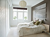 Scatter cushions on double bed against grey-painted wall in bright, modern bedroom