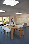 Minimalistischer Esstisch aus Holz und weiße Schalenstühle in zeitgenössischem Wohnraum mit Oberlichtern in Decke