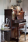 Delicate metal side table next to piano with lit candles in sconces mounted on front in corner