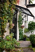 Classic coffered door and glass porch with old, wrought iron frame on vine-covered facade