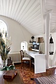 Classic lamp on desk in corner of living room below curved, wood-clad ceiling
