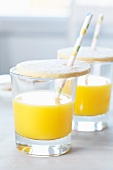 Glas Orangensaft mit Keks-Deckel und Strohhalm