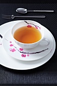 A place setting for afternoon tea, with a flower design, on a black surface