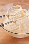 Cake mixture in a glass bowl and on the whisks of the mixer