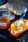 A slice of bread with butter and marmalade, a jar of marmalade and a butter wrapper