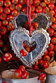 Small silver hearts hanging on red ribbons against rosehips