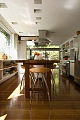 Viel Fensterfläche in der weissen, modernen Küche mit 80er Jahre Barhockern an der Naturholztheke