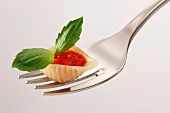 A pasta shell with tomato sauce and basil on a fork
