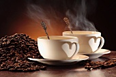 Zwei dampfende Kaffeetassen und Kaffeebohnen