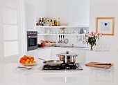A contemporary white kitchen with a gas hob and various cooking utensils