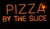 A neon sign at a pizzeria in the evening